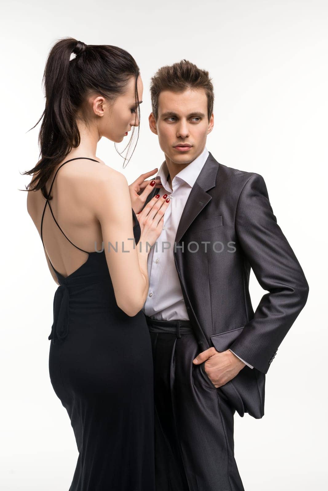 Beautiful woman in evening dress undressing her man shot