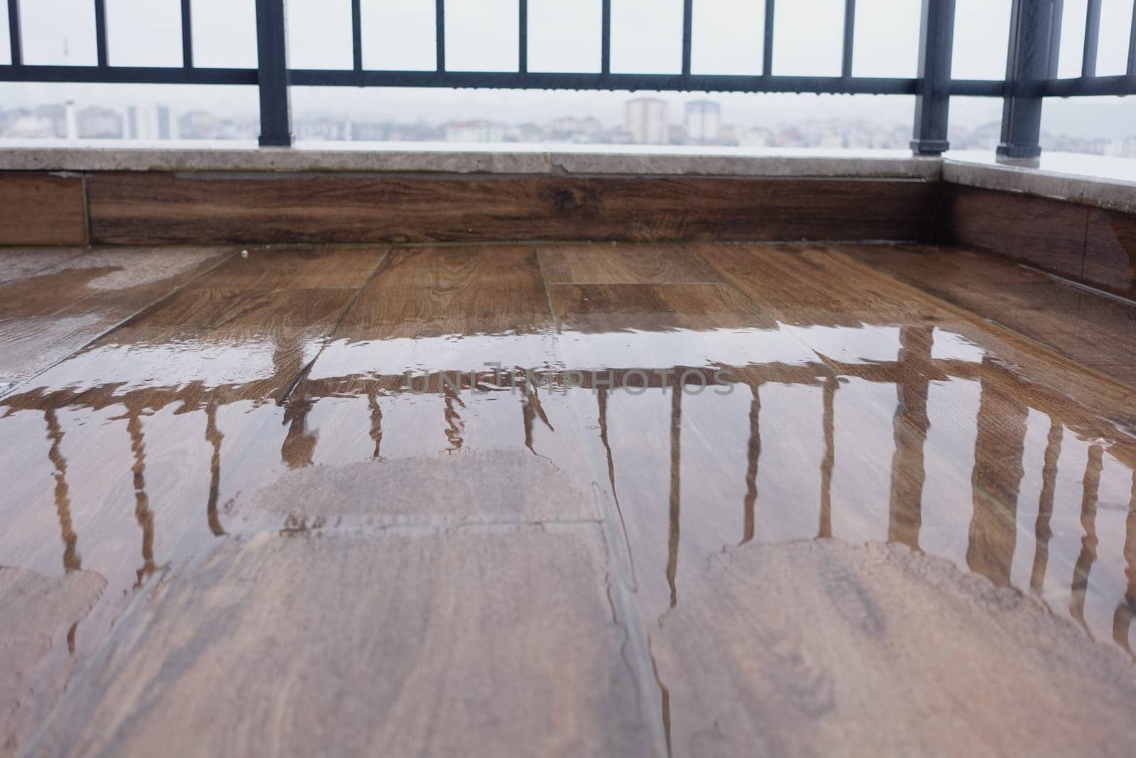 The reflective surface of a wooden floor features railings and offers a view of the clouds