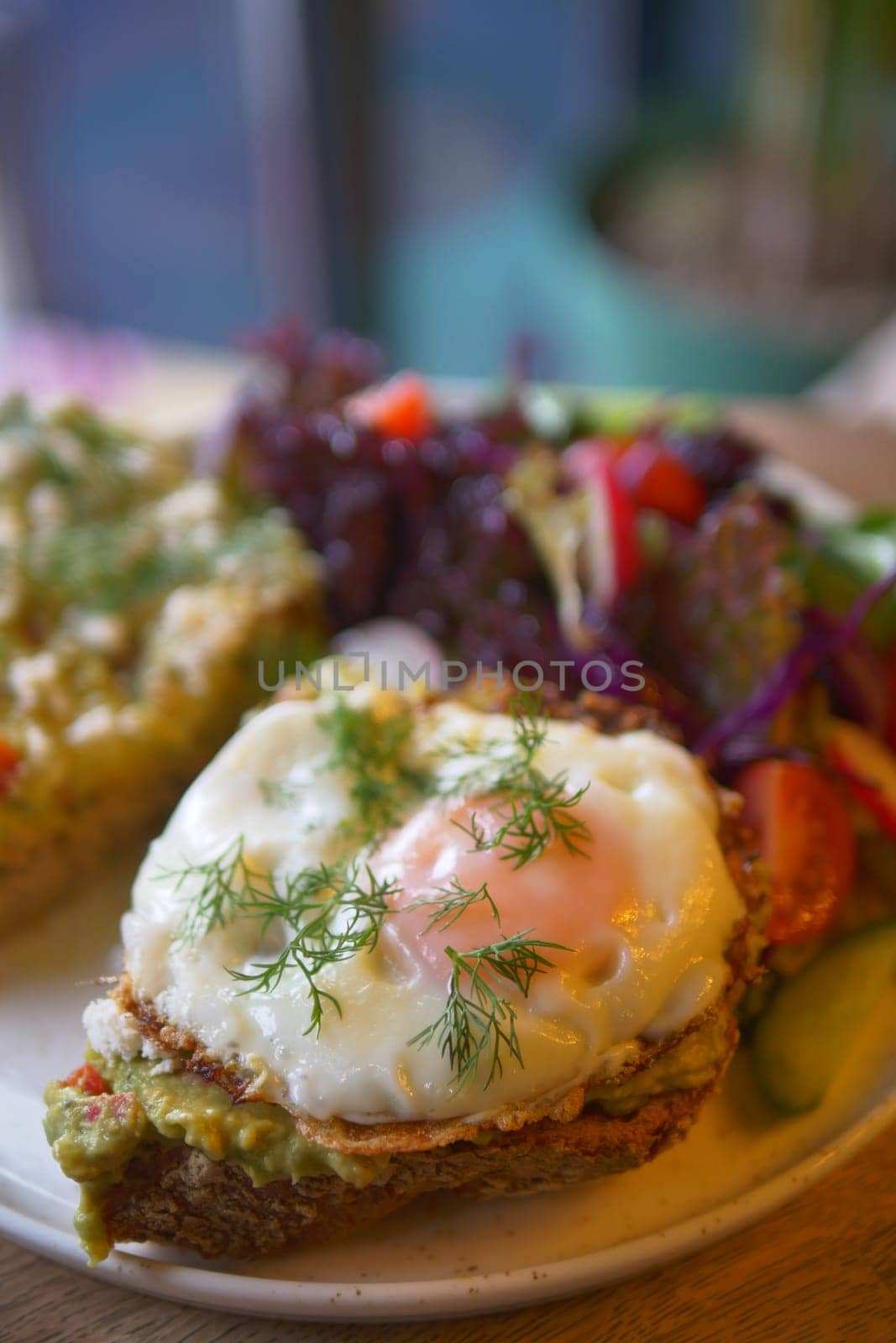 Enjoy avocado toast with a poached egg, served with a fresh mixed salad on the side