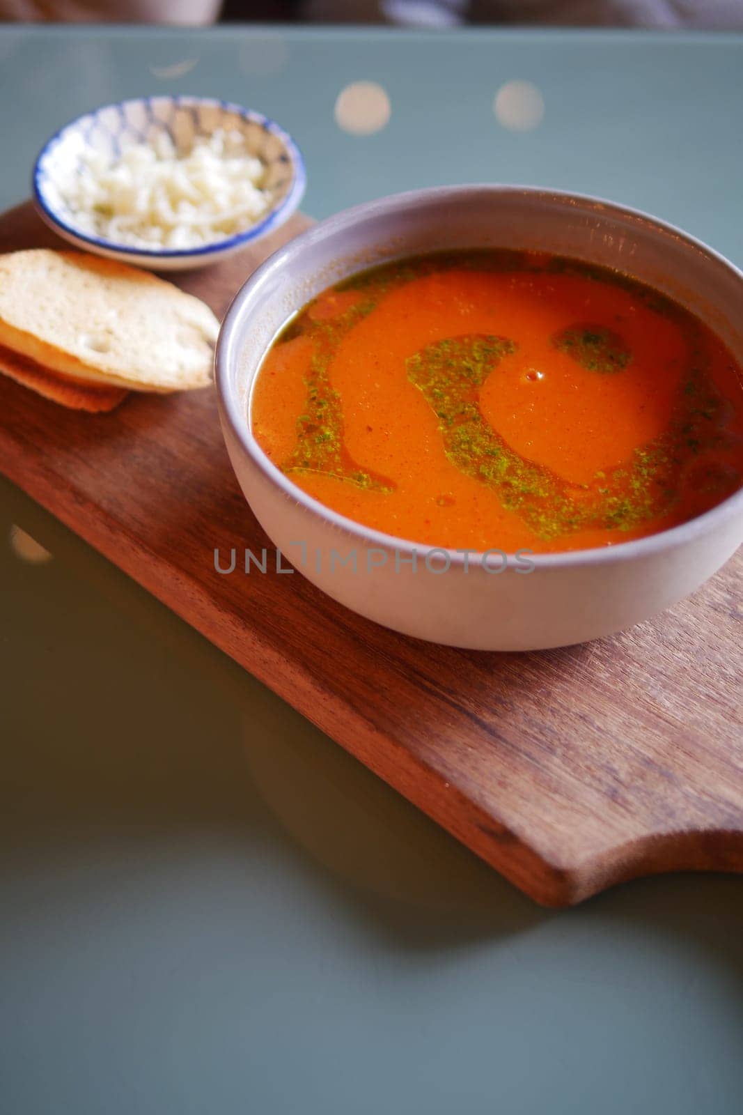 A bowl of hearty soup is beautifully served alongside crisp tortilla chips and melted cheese