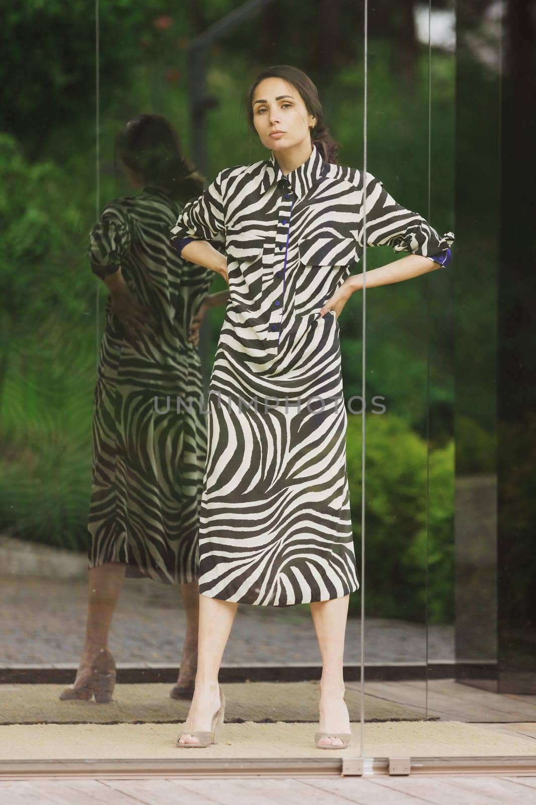 High fashion photo of a beautiful elegant young woman in a pretty zebra print dress posing outdoor. Slim figure by sarymsakov