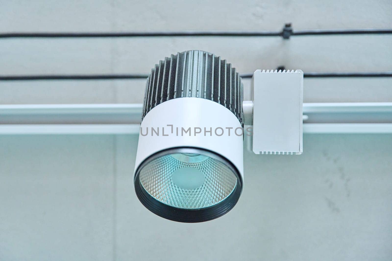 Close-up of white LED spotlight, on ceiling rail system, directional rotating light. Modern interior design