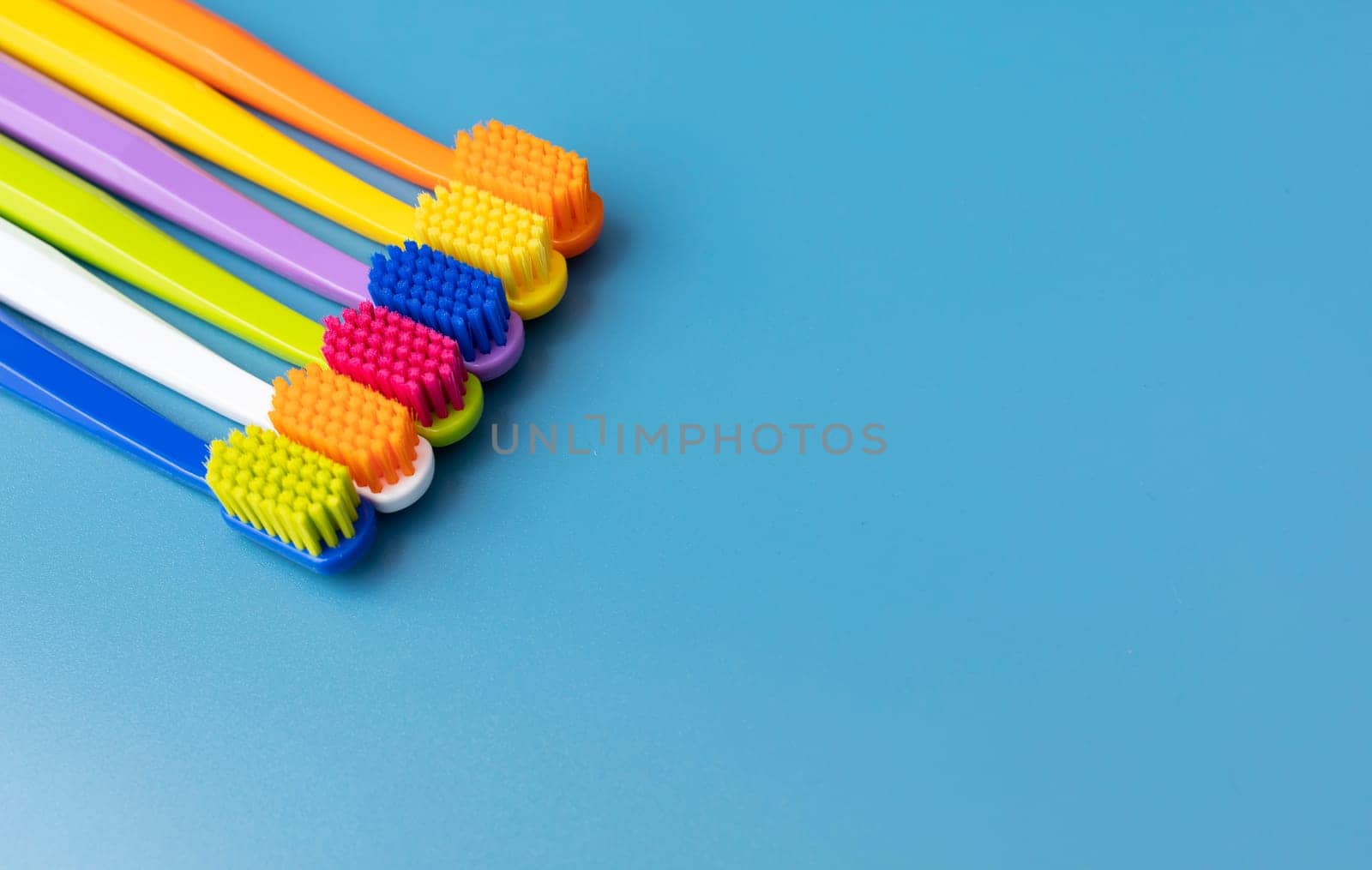 Design Set of Colorful Antibacterial Toothbrushes on Blue Background. View From Above. Copy Space For Text. Set for Dental Hygiene, Bathing Self Care Products. Horizontal Plane. High quality photo