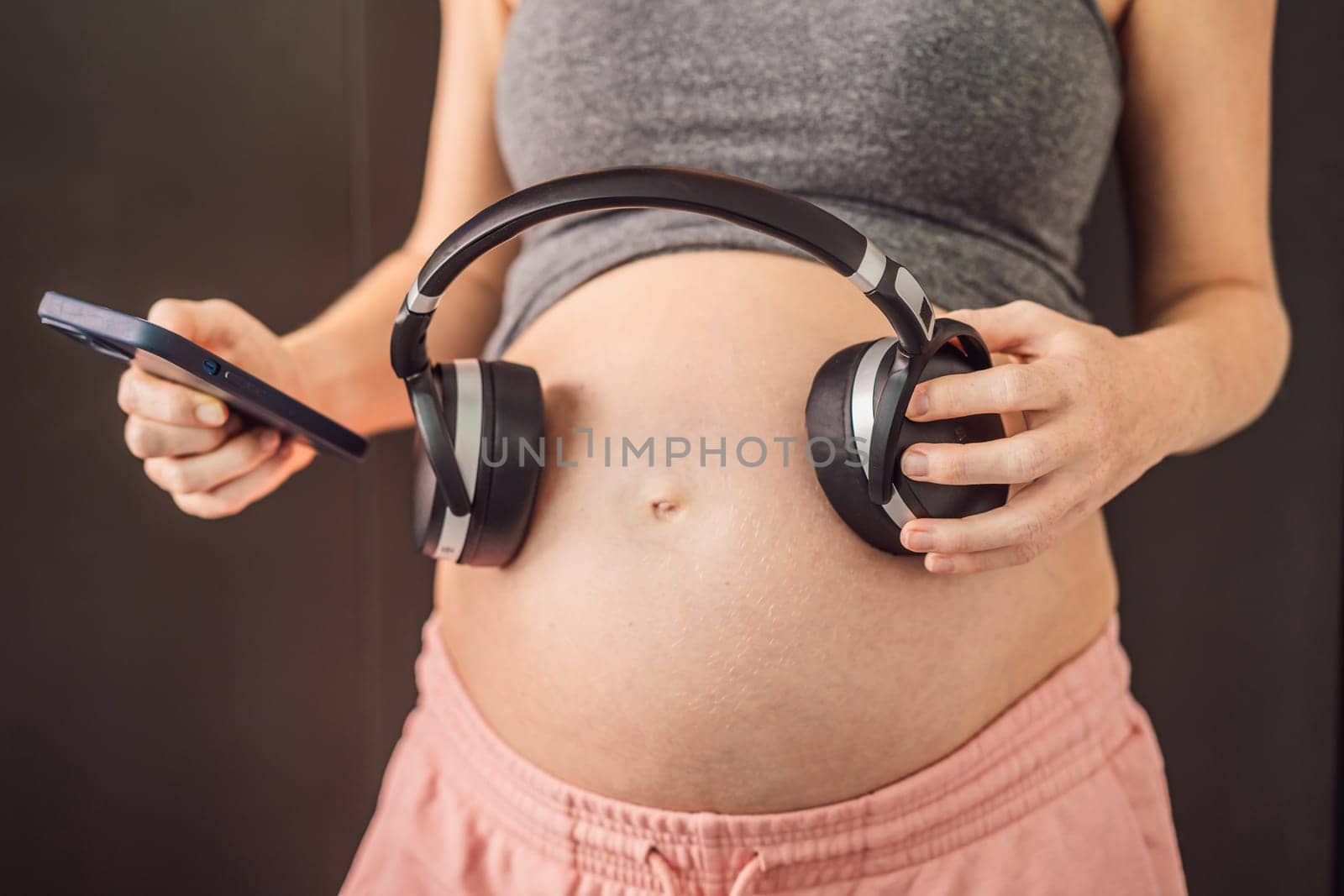 Melodies in the womb: Headphones placed on a pregnant belly, bonding through music, a heartwarming connection between mother and baby.