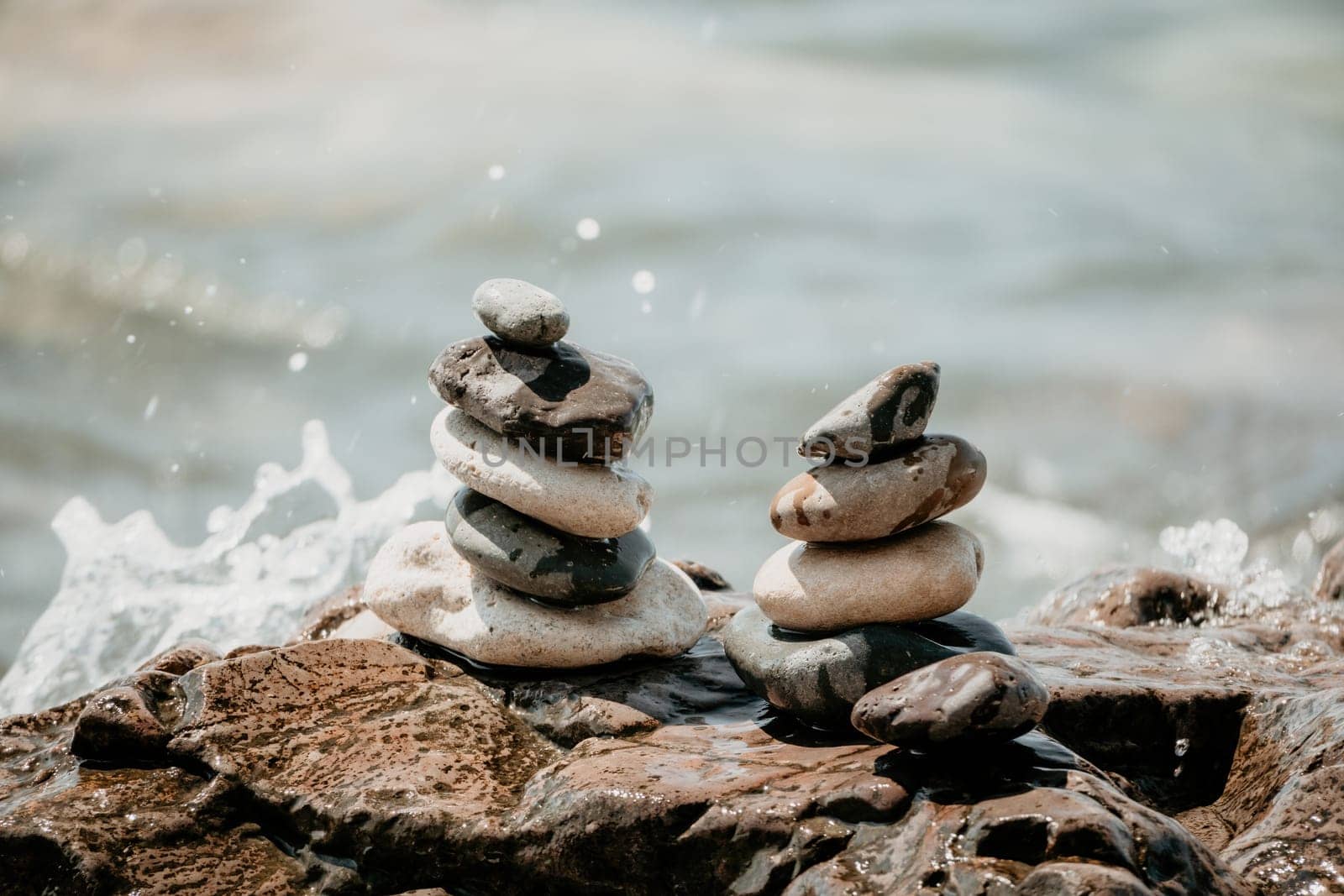 Pyramid stones on the seashore with warm sunset on the sea background. Happy holidays. Pebble beach, calm sea, travel destination. Concept of happy vacation on the sea, meditation, spa, calmness.