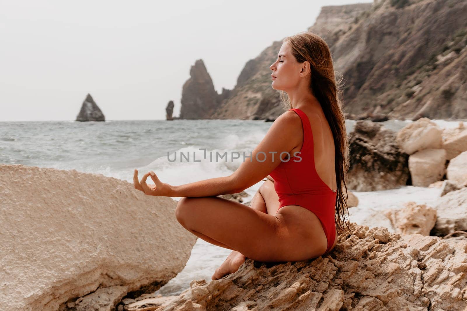 Woman sea yoga. Back view of free calm happy satisfied woman with long hair standing on top rock with yoga position against of sky by the sea. Healthy lifestyle outdoors in nature, fitness concept.