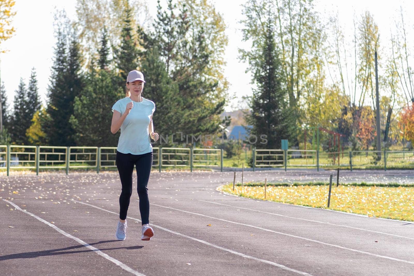 A young beautiful woman in sportswear plays sports at a local stadium. Exercise, jog and exercise at the beginning of the day. Healthy and active lifestyle.