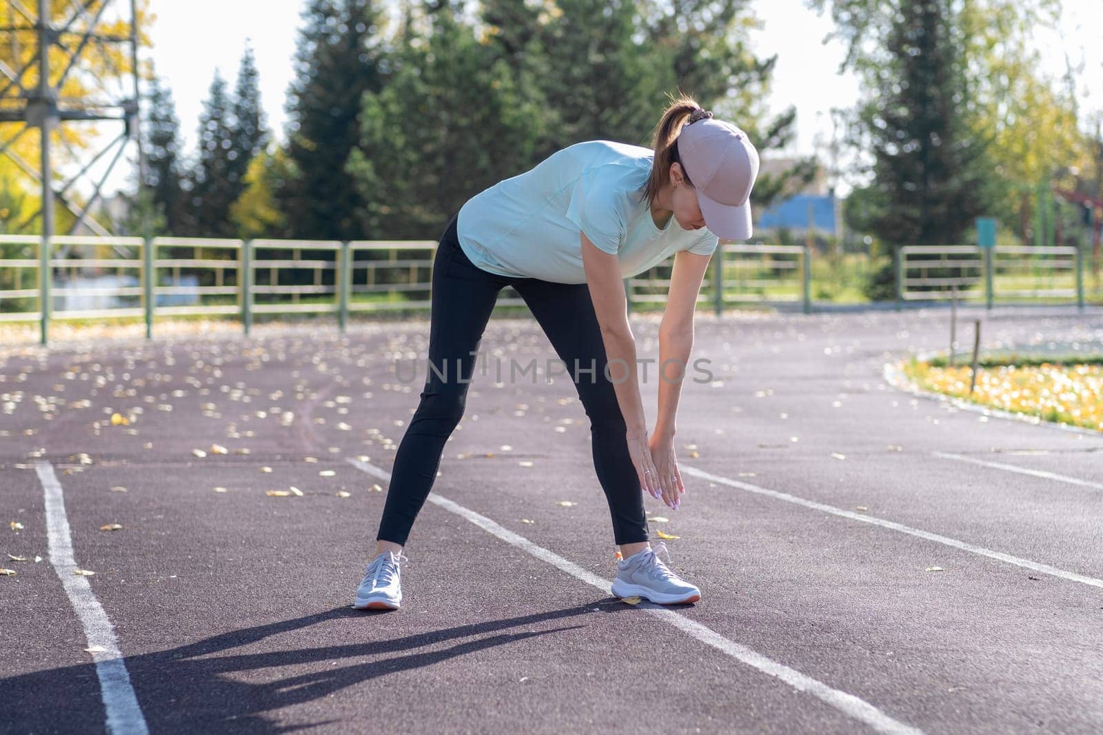 A young beautiful woman in sportswear plays sports at a local stadium by AnatoliiFoto