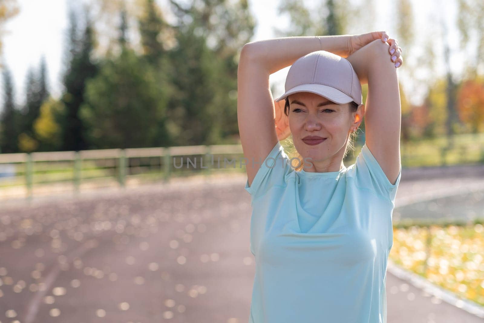 A young beautiful woman in sportswear plays sports at a local stadium by AnatoliiFoto