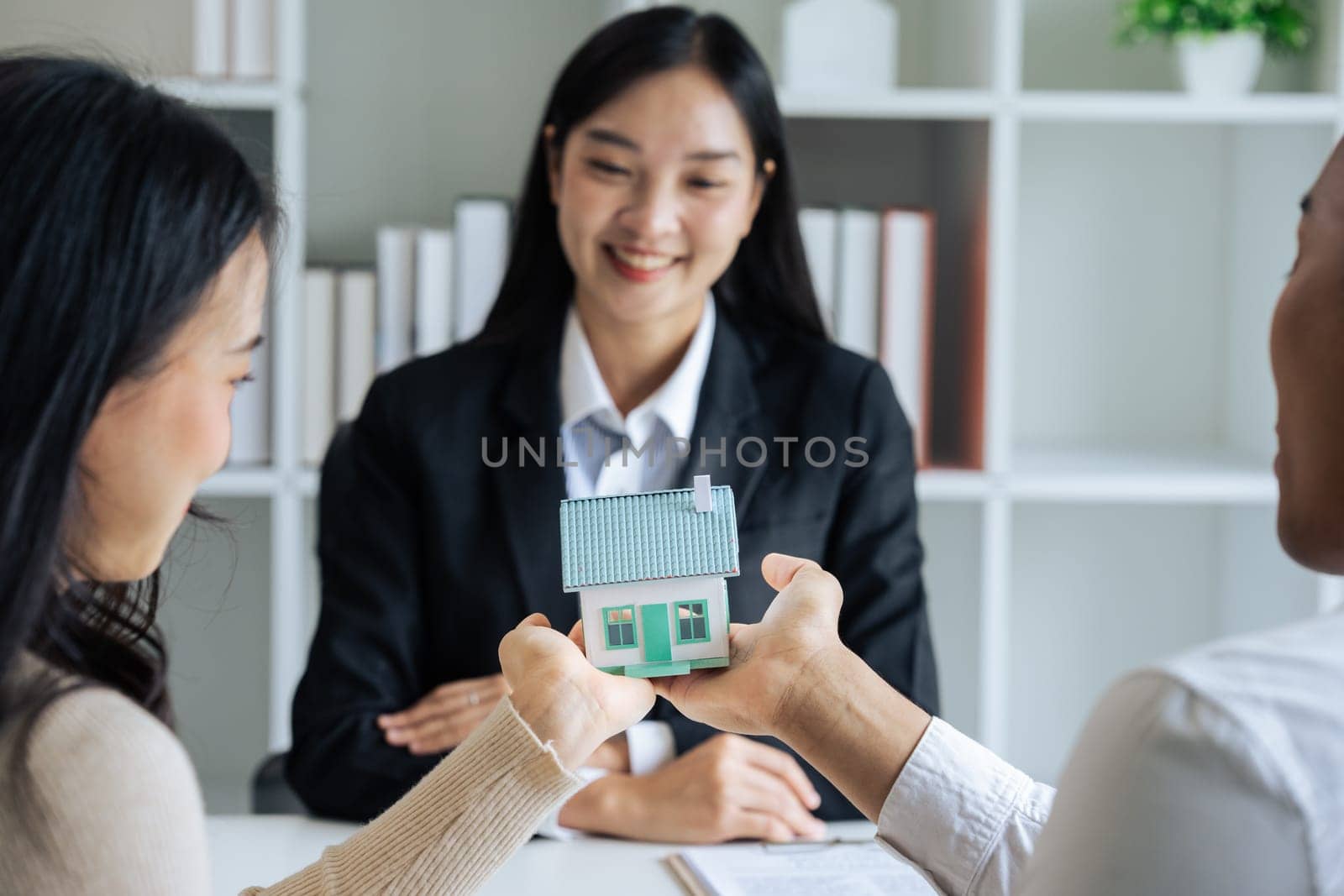 Young couple holds model house together after successfully signing for house together by itchaznong