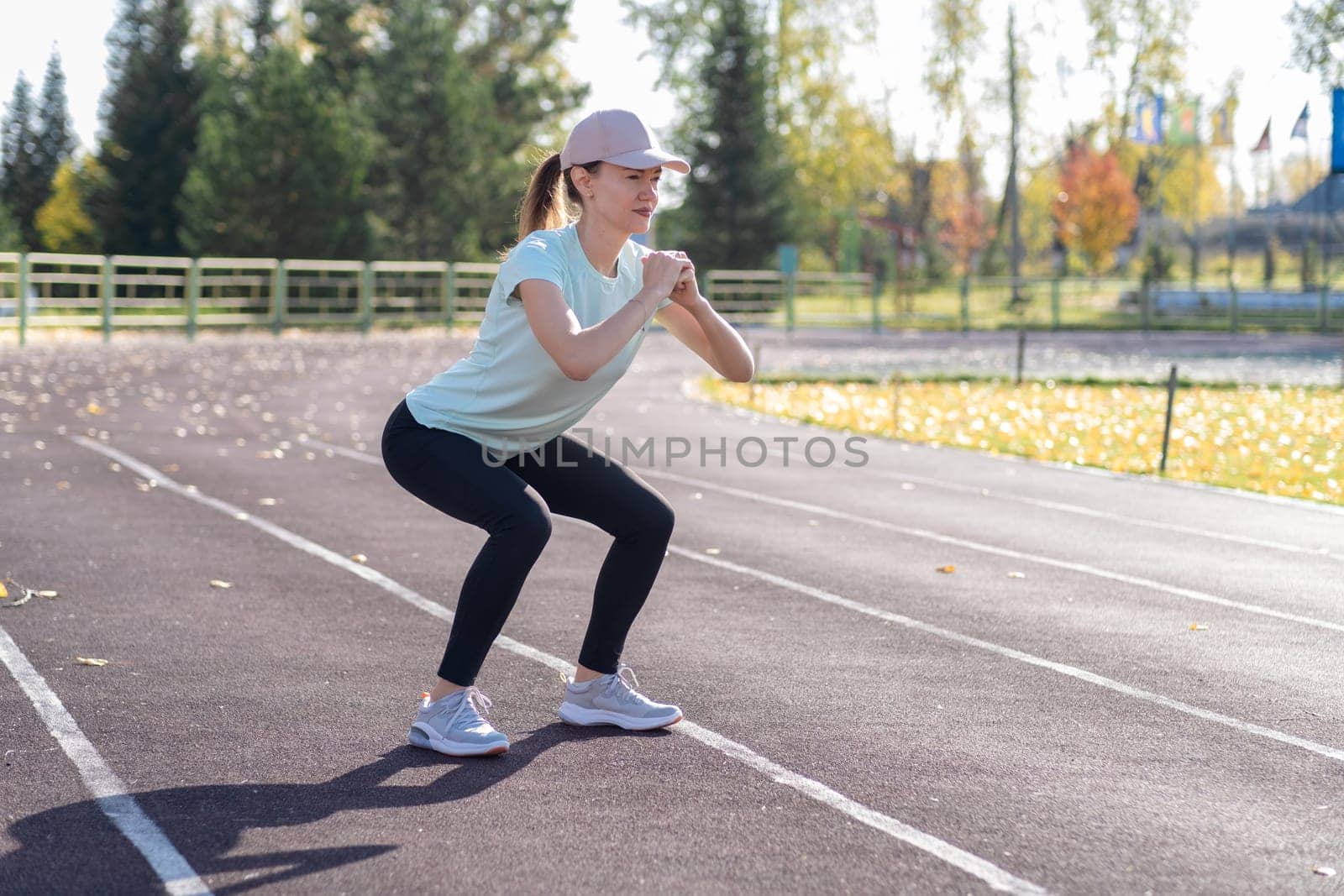 A young beautiful woman in sportswear plays sports at a local stadium by AnatoliiFoto