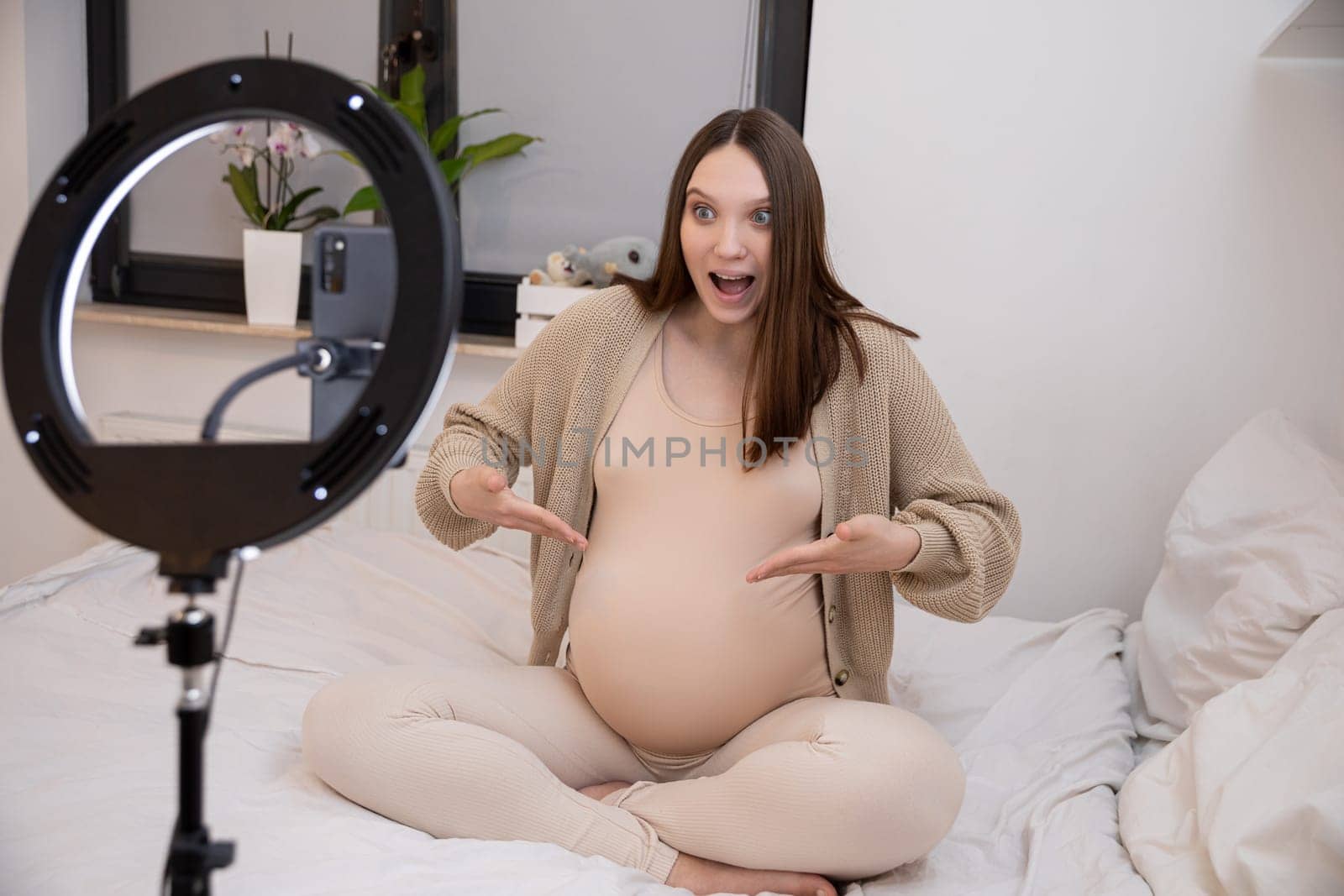 A joyful and radiant pregnant woman proudly showcasing her baby bump in a beautifully cozy bedroom setting