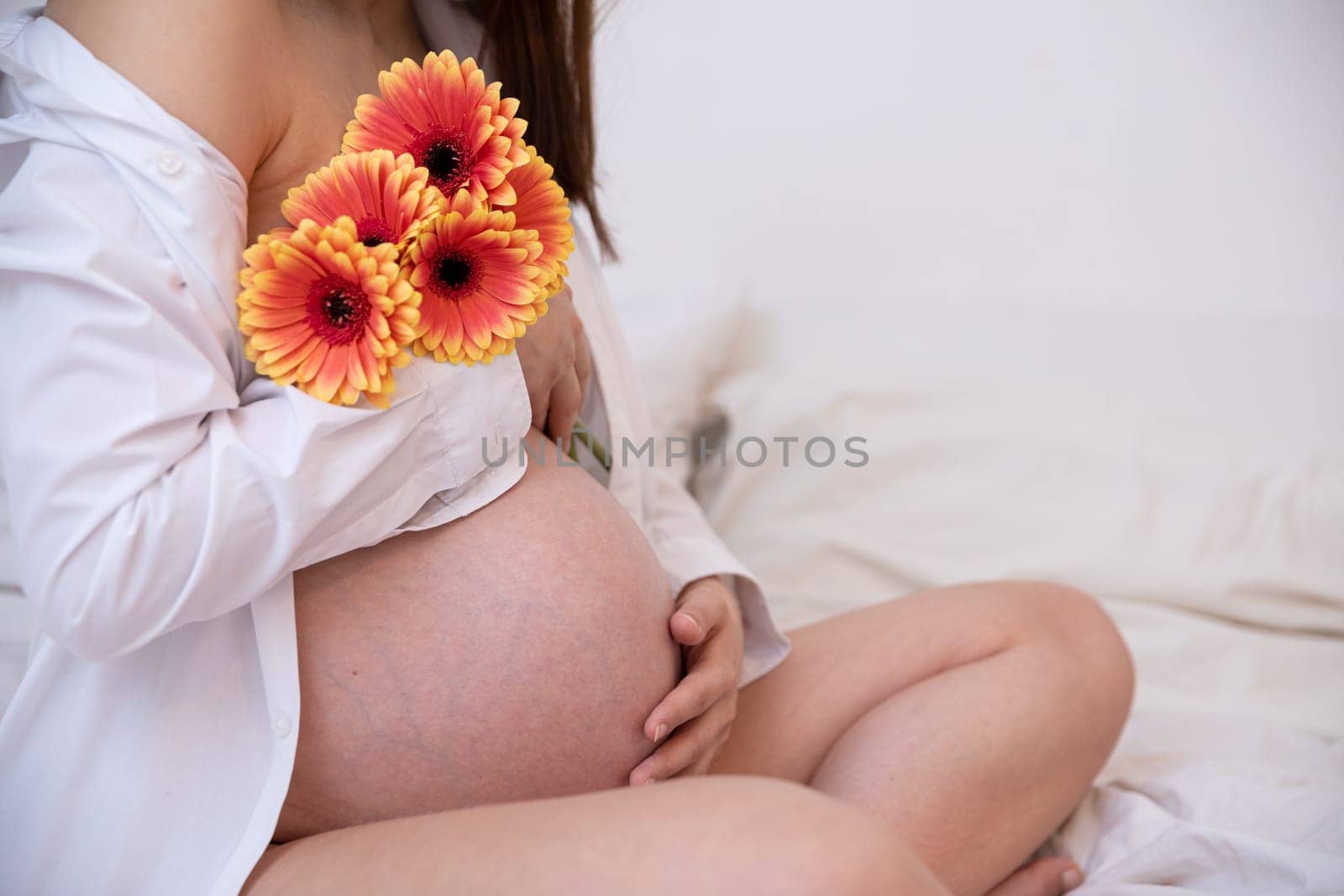 A beautiful pregnant woman cradles her belly gently with vibrant flowers, symbolizing new life and motherhood
