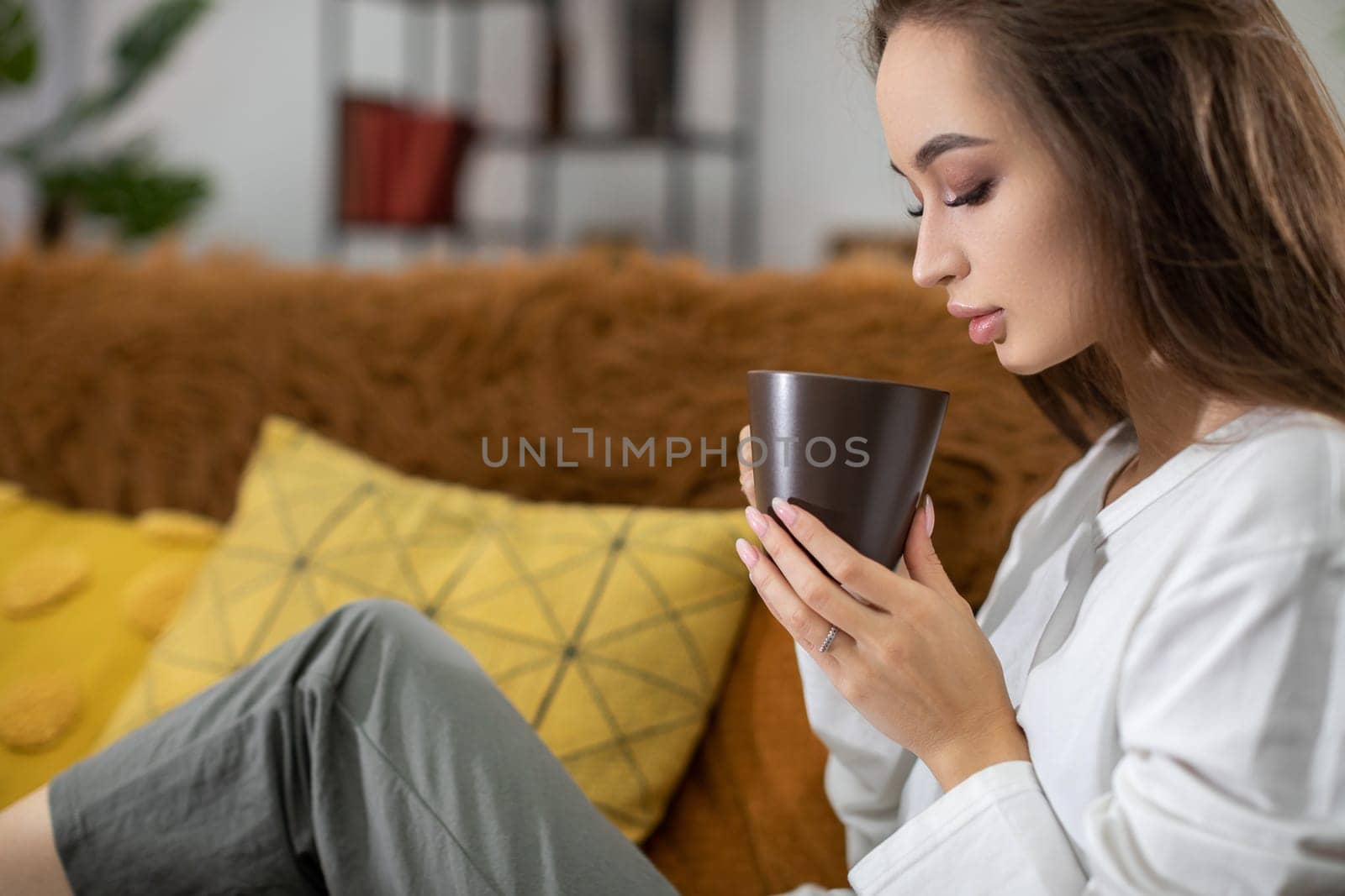 In a serene atmosphere, a woman sips her tea, embracing a cozy setting of relaxation and mindfulness