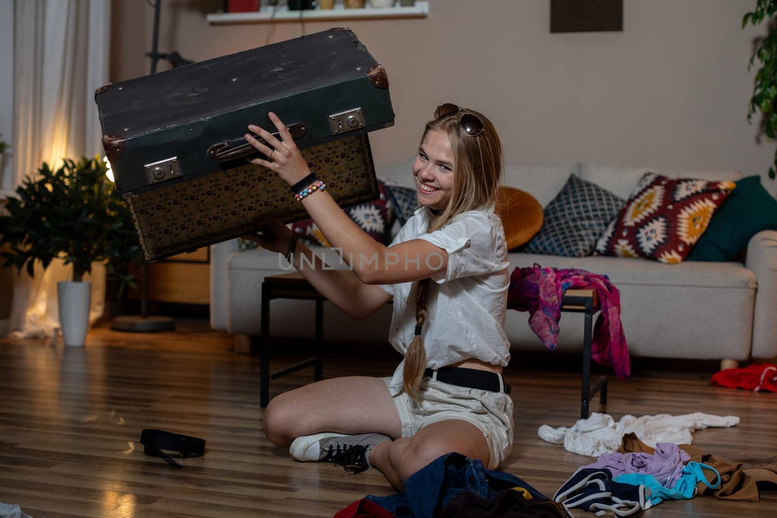 A young woman is energetically unpacking a vintage suitcase in her stylish and inviting living room space