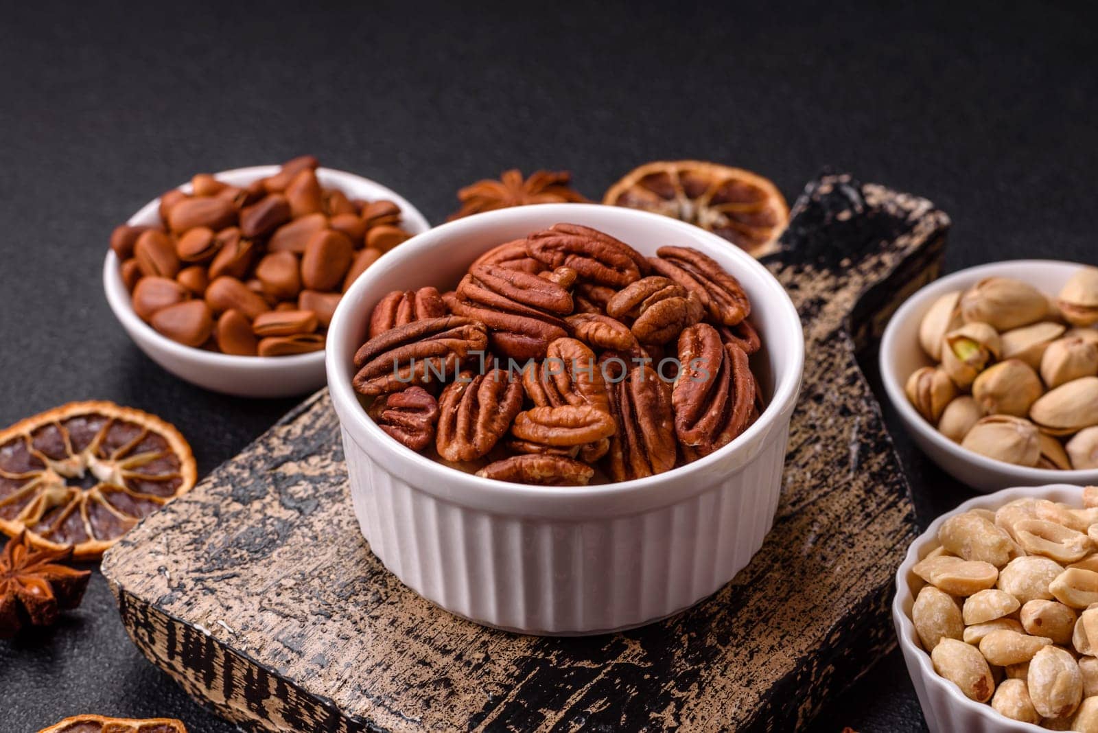 Delicious nutritious pecan nuts in ceramic bowl on dark concrete background