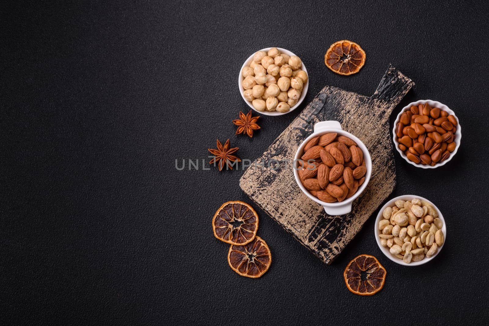 Delicious nutritious almond nuts in ceramic bowl on dark concrete background