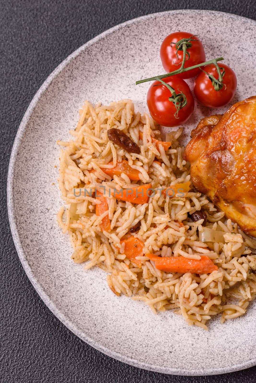 Delicious fresh pilaf with rice, carrots, meat, onions, spices and berries on a ceramic plate on a dark concrete background