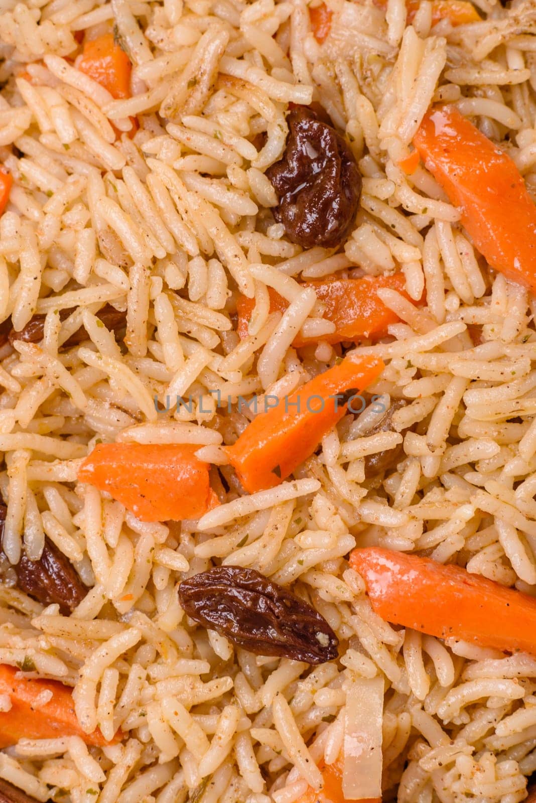 Delicious fresh pilaf with rice, carrots, meat, onions, spices and berries on a ceramic plate on a dark concrete background