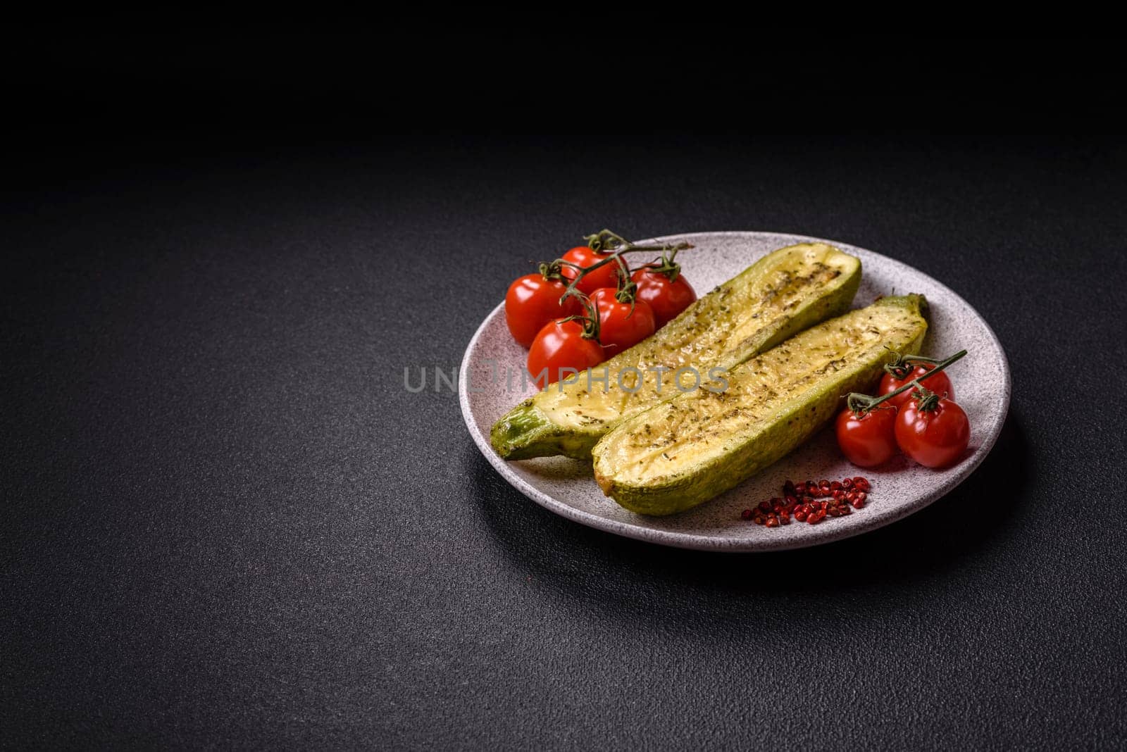 Delicious zucchini cut into two halves baked with salt, spices and herbs on a dark concrete background