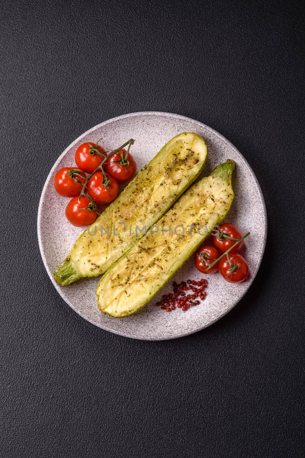 Delicious zucchini cut into two halves baked with salt, spices and herbs on a dark concrete background