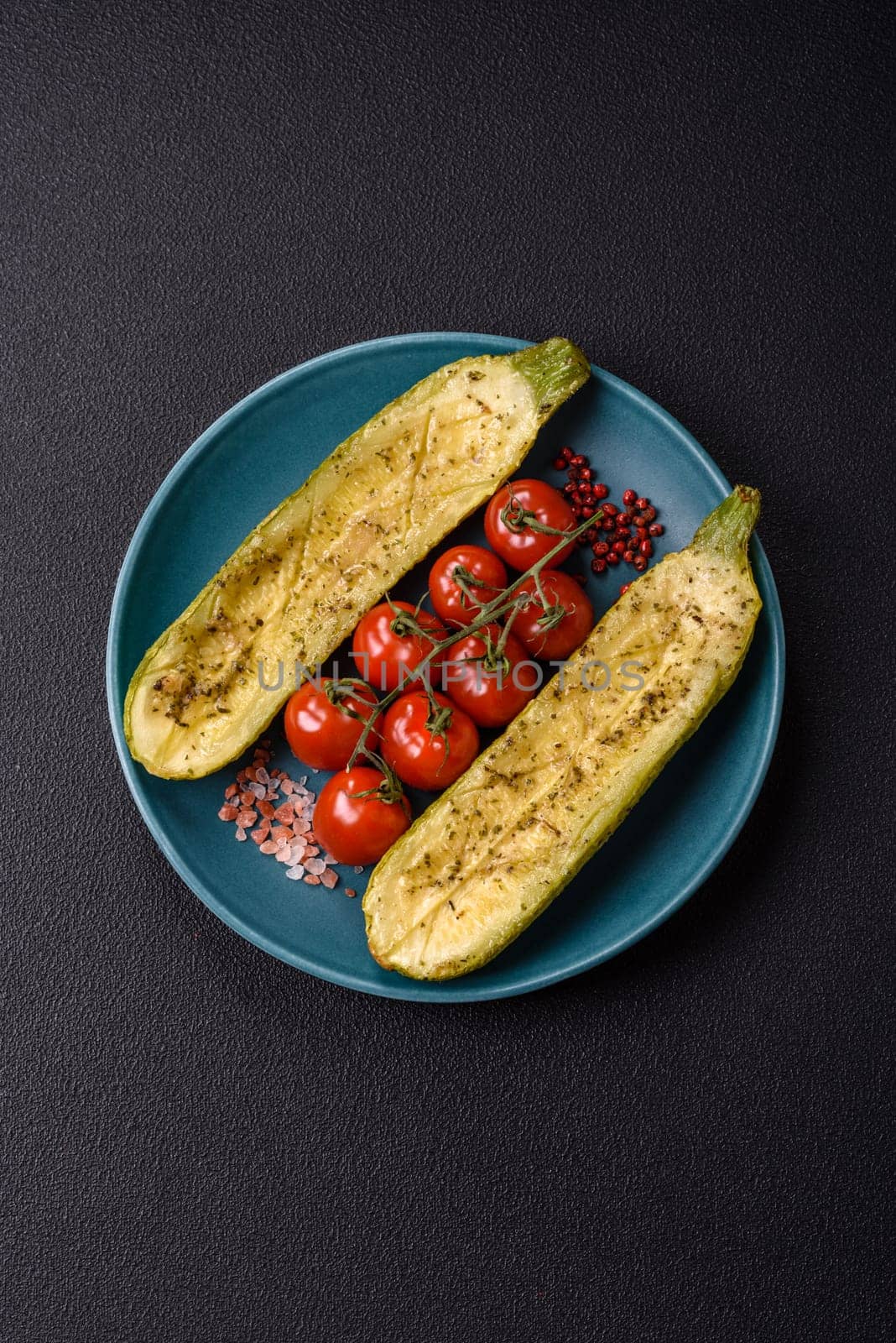 Delicious zucchini cut into two halves baked with salt, spices and herbs on a dark concrete background
