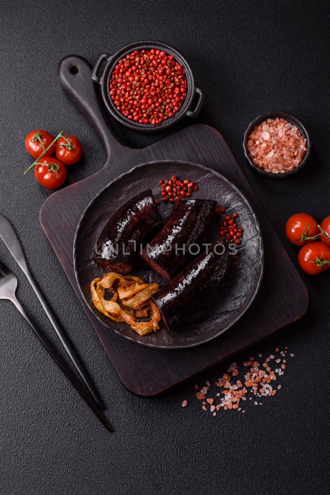 Delicious black blood sausage or black pudding with spices and herbs grilled on a black concrete background