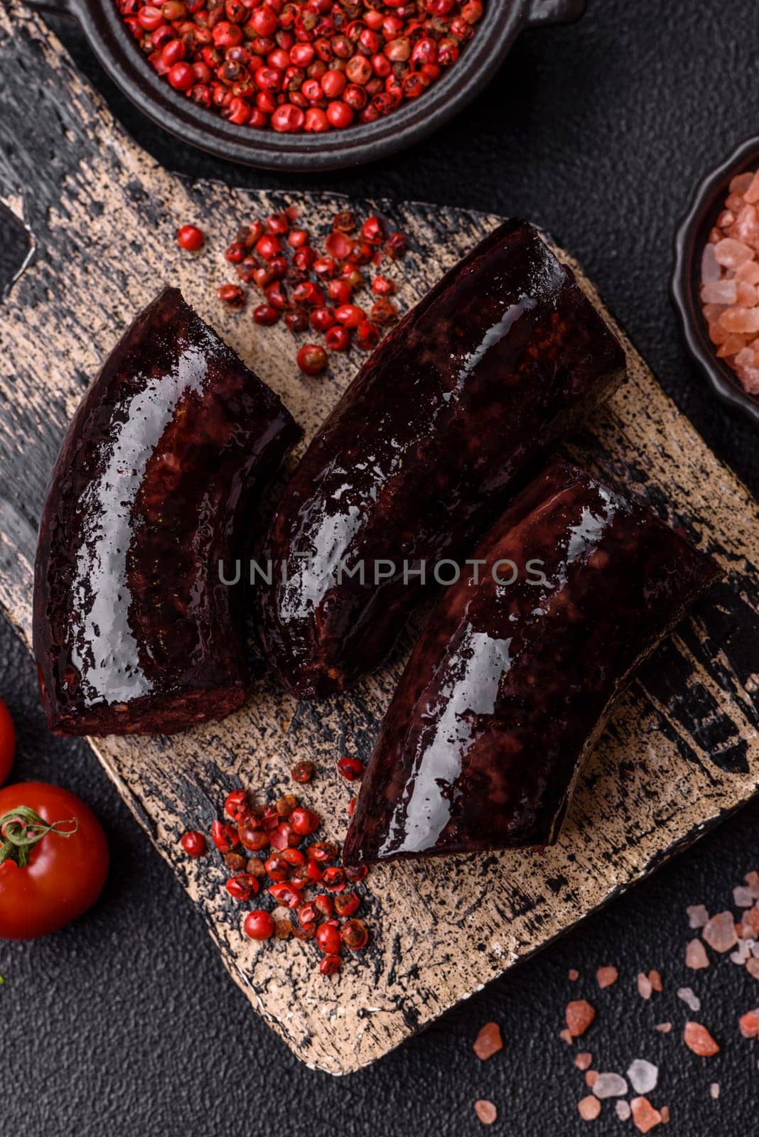 Delicious black blood sausage or black pudding with spices and herbs grilled on a black concrete background