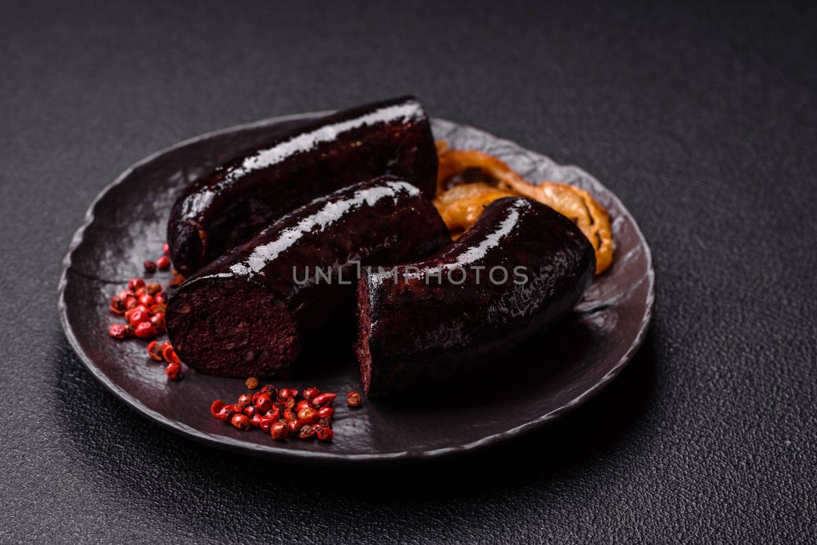 Delicious black blood sausage or black pudding with spices and herbs grilled on a black concrete background