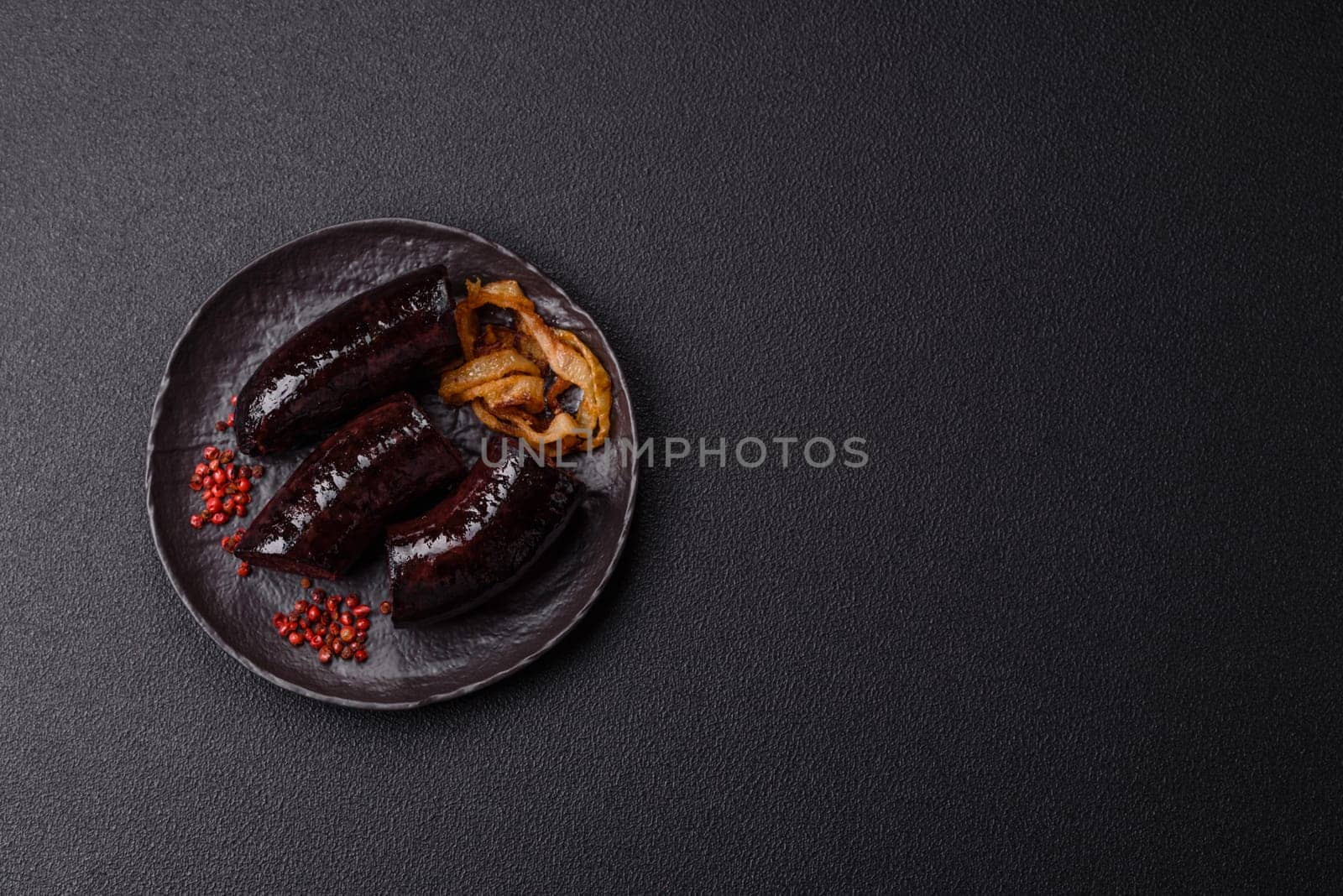 Delicious black blood sausage or black pudding with spices and herbs grilled on a black concrete background
