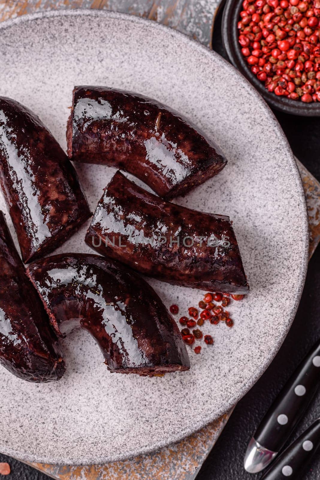 Delicious black blood sausage or black pudding with spices and herbs grilled on a black concrete background
