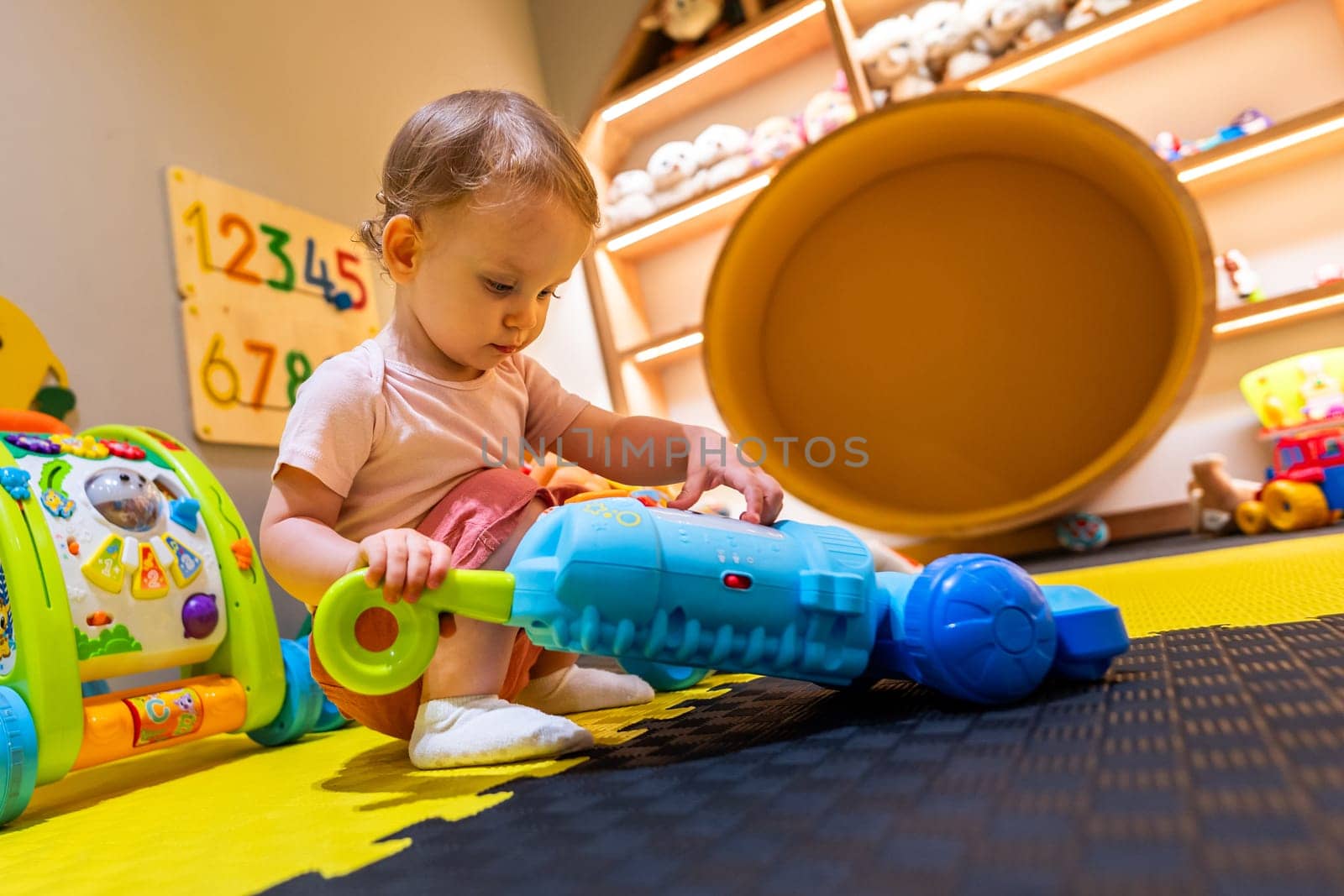 Kid exploring with a toy vacuum cleaner in a cozy and colorful playroom for early childhood learning and fun