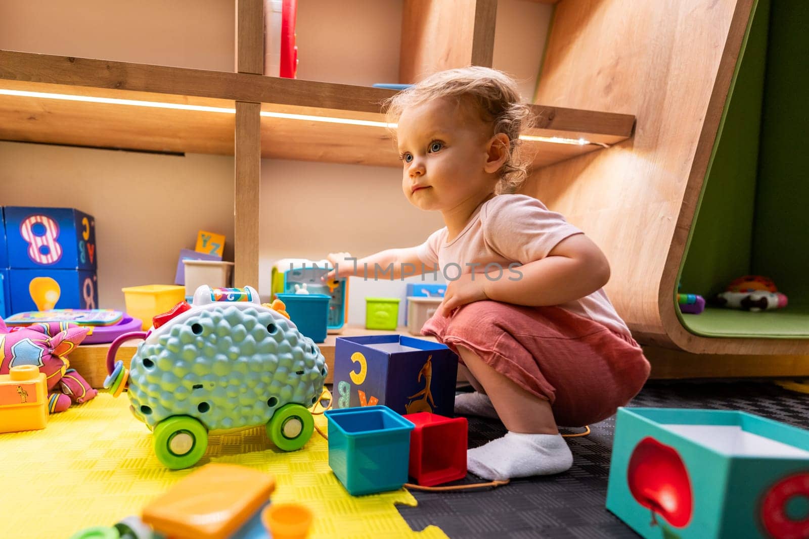 Little child playing with stacking blocks and interactive toys in a bright learning space