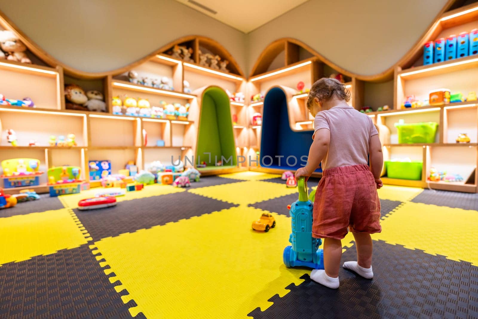 Child exploring a bright and organized indoor playroom with toys and activity stations