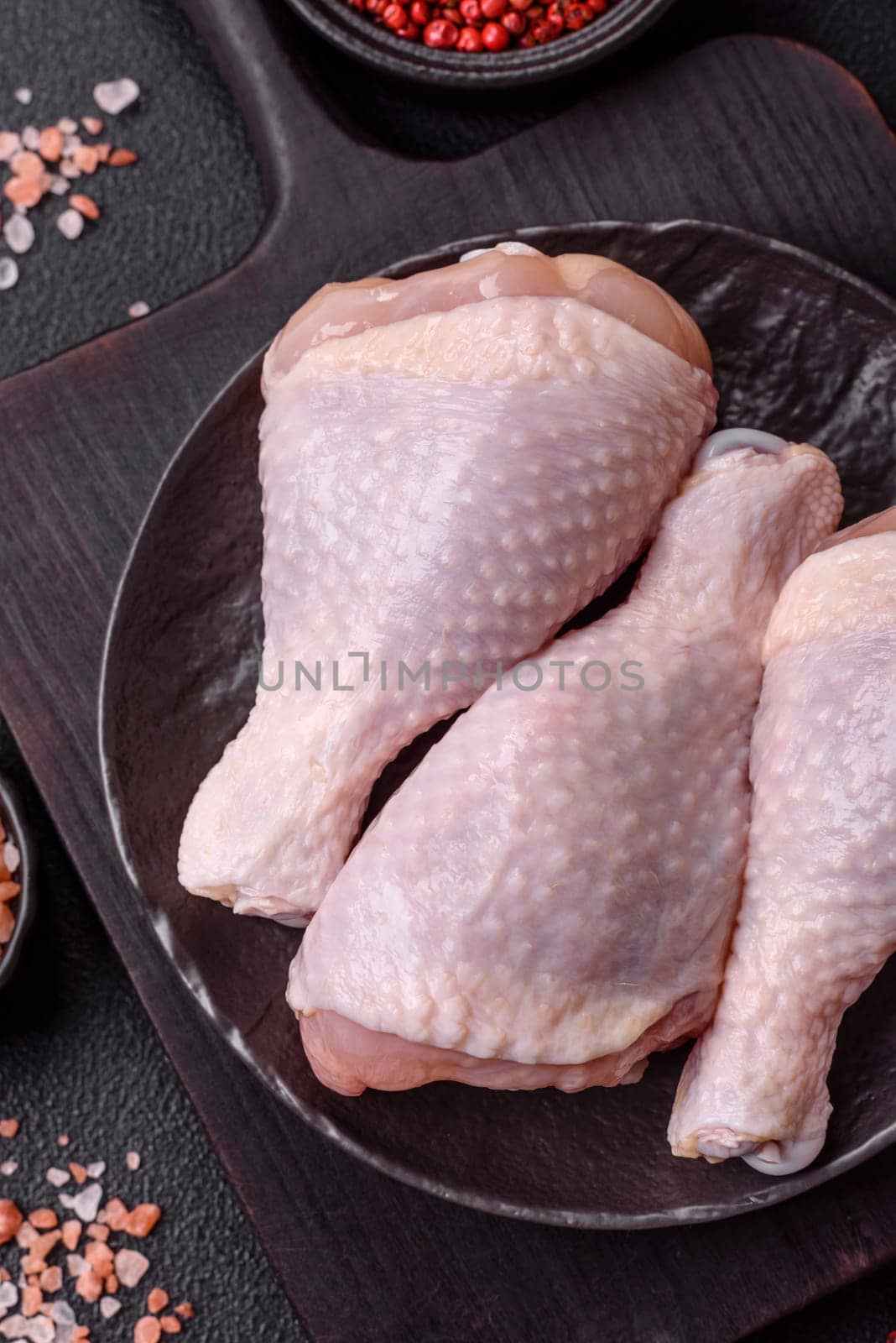 Raw chicken legs with salt, spices and herbs prepared for grilling