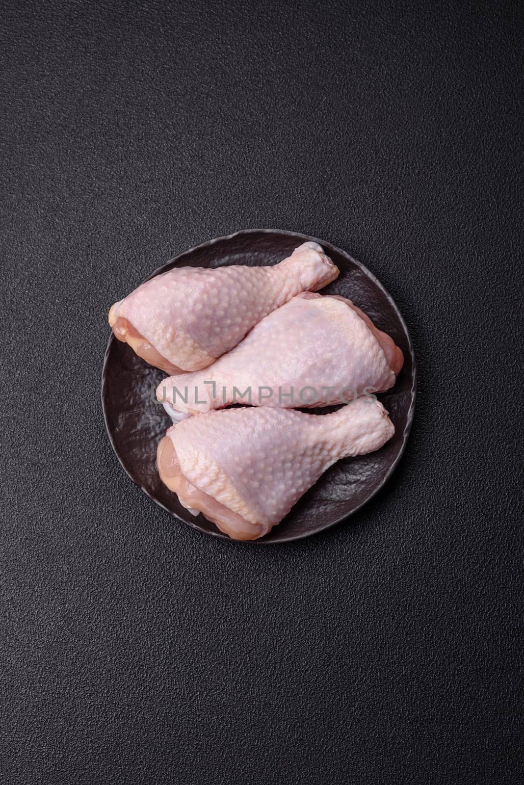 Raw chicken legs with salt, spices and herbs prepared for grilling