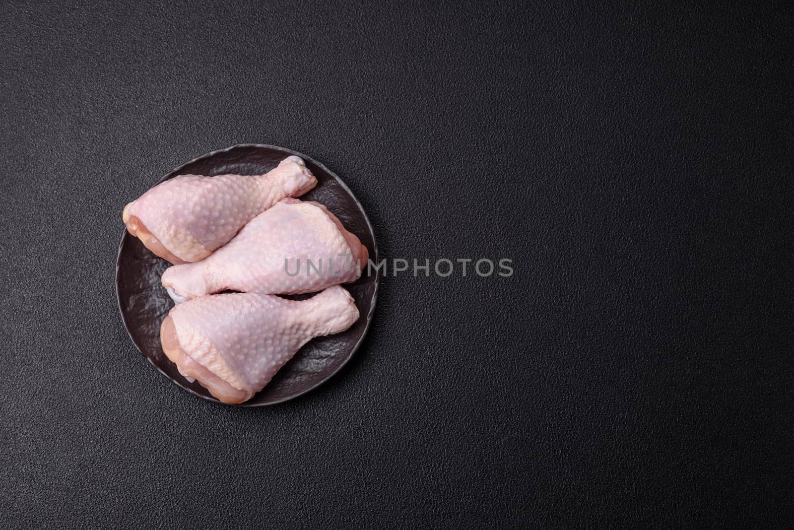 Raw chicken legs with salt, spices and herbs prepared for grilling