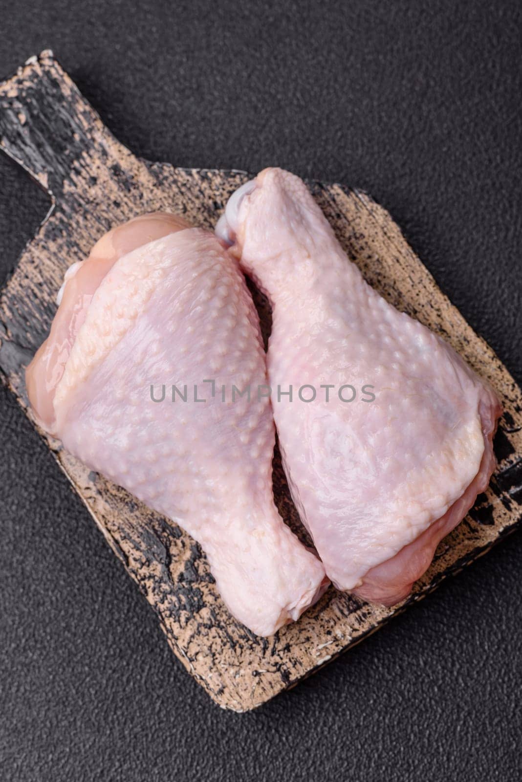 Raw chicken legs with salt, spices and herbs prepared for grilling
