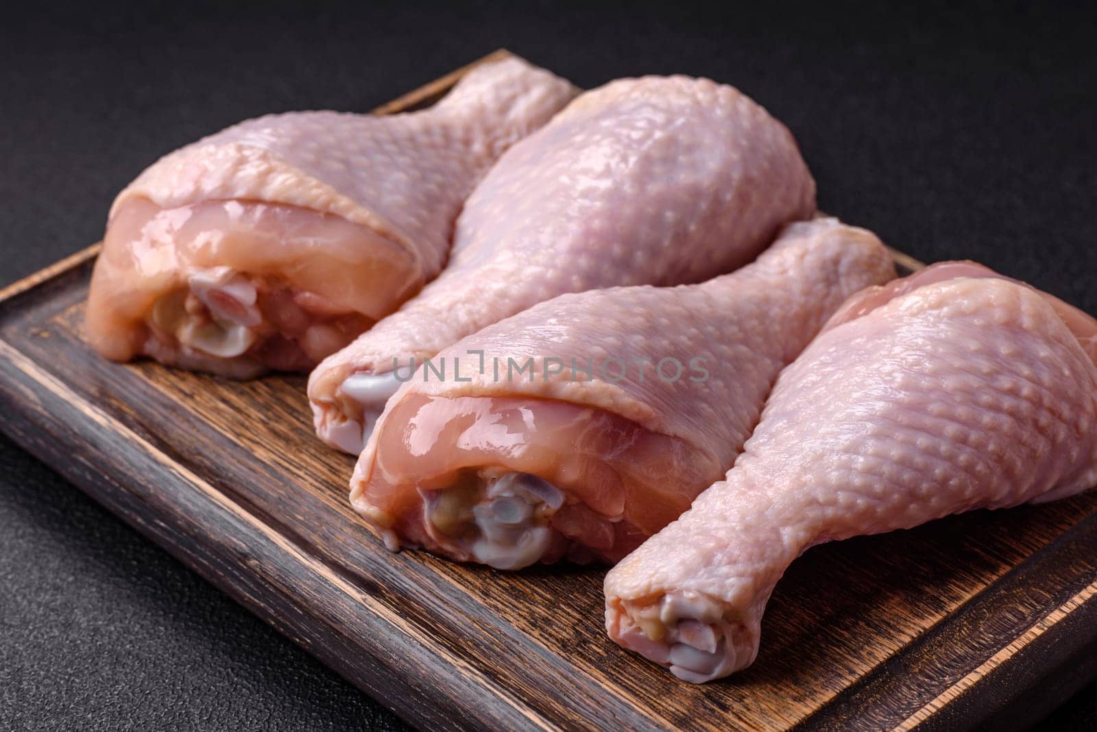 Raw chicken legs with salt, spices and herbs prepared for grilling