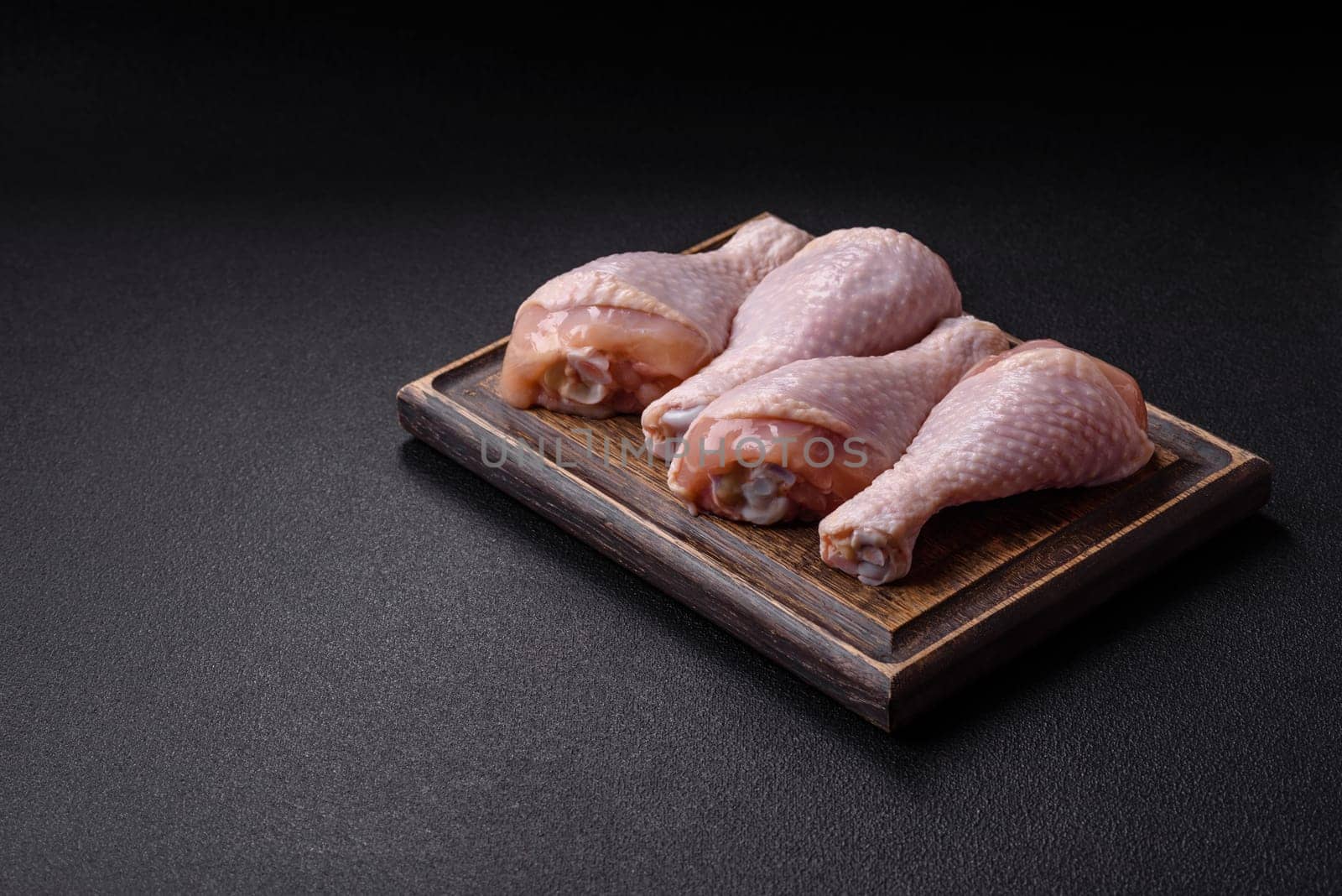 Raw chicken legs with salt, spices and herbs prepared for grilling