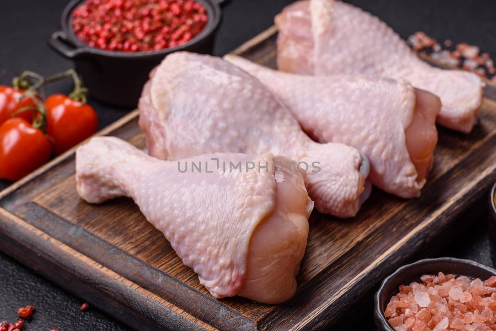 Raw chicken legs with salt, spices and herbs prepared for grilling