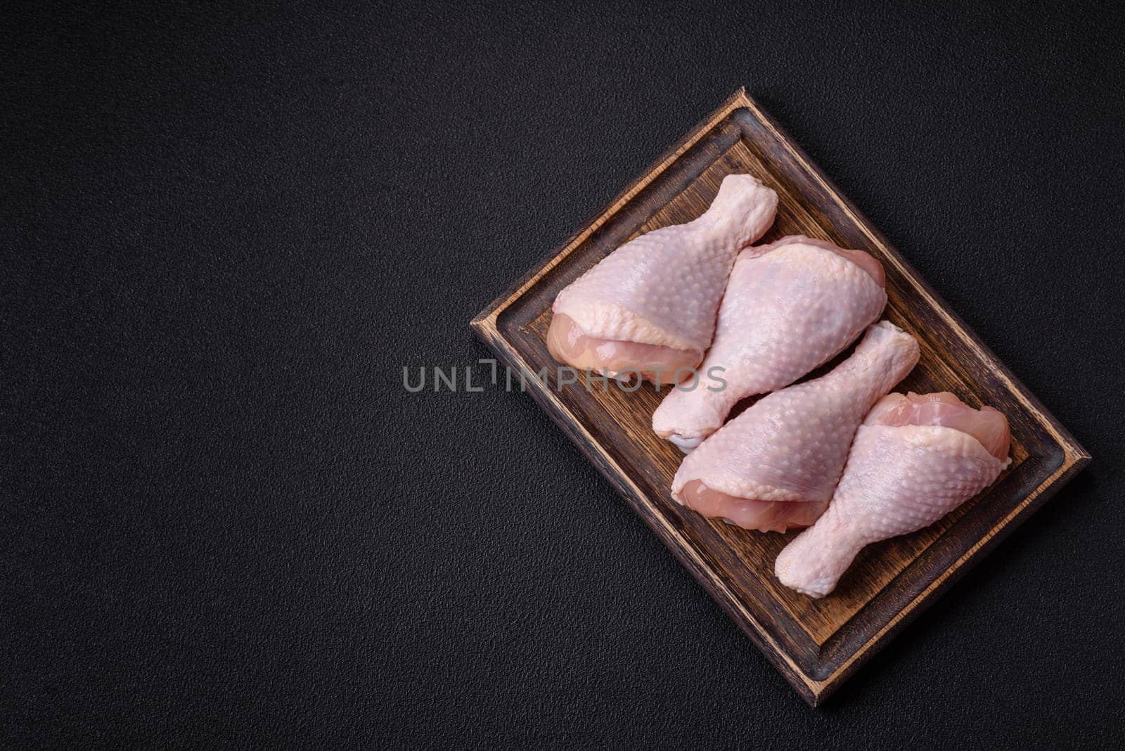 Raw chicken legs with salt, spices and herbs prepared for grilling