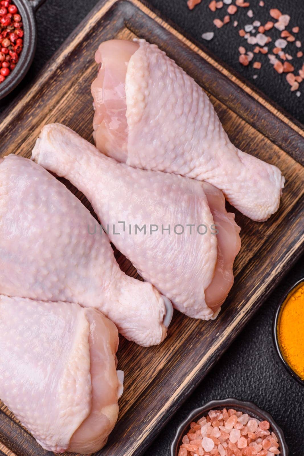 Raw chicken legs with salt, spices and herbs prepared for grilling