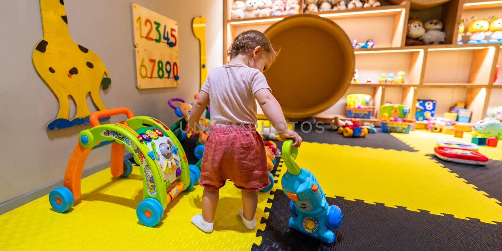 Child using a toy vacuum cleaner for pretend cleaning in a vibrant playroom with interactive learning toys
