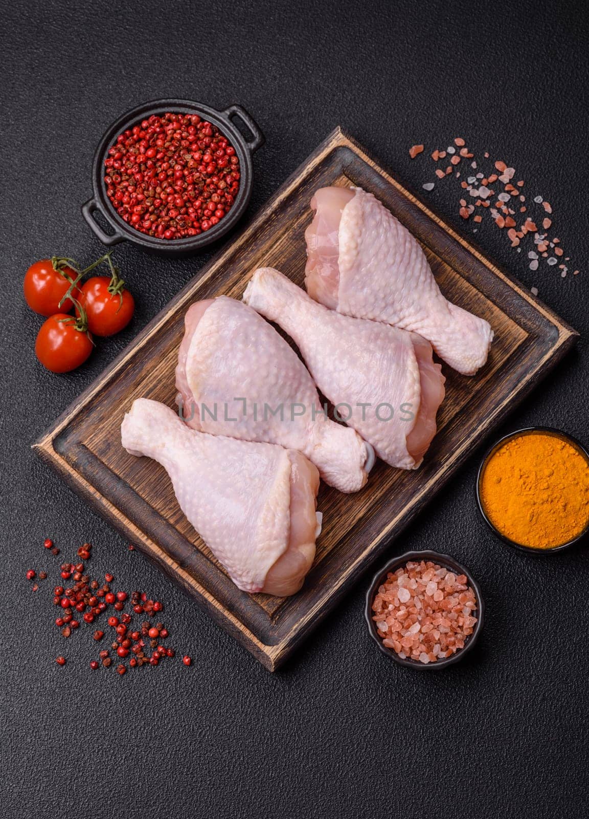 Raw chicken legs with salt, spices and herbs prepared for grilling