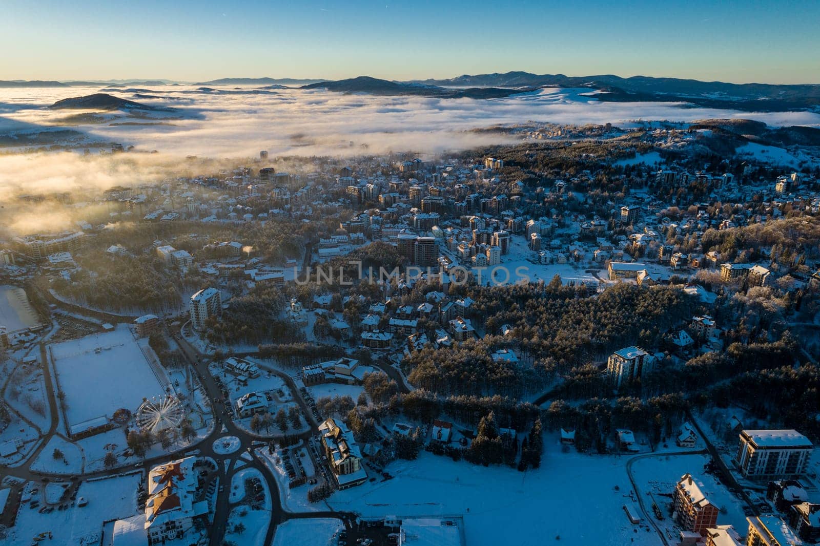 Panoramic aerial view of Zlatibor town and low cloud over Zlatibor Mountain at winter sunset, Cajetina, Serbia.