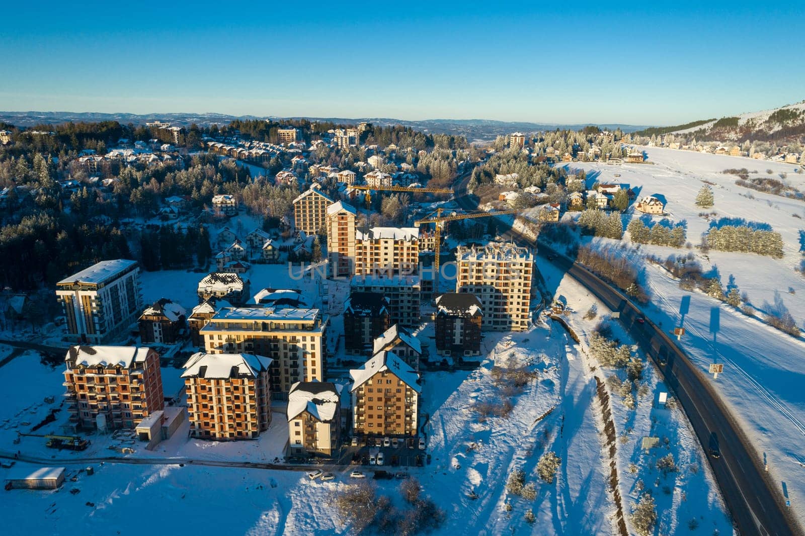 Panoramic aerial view of new buildings for sale on Zlatibor town and clear sky over Zlatibor Mountain at winter sunset, Cajetina, Serbia.