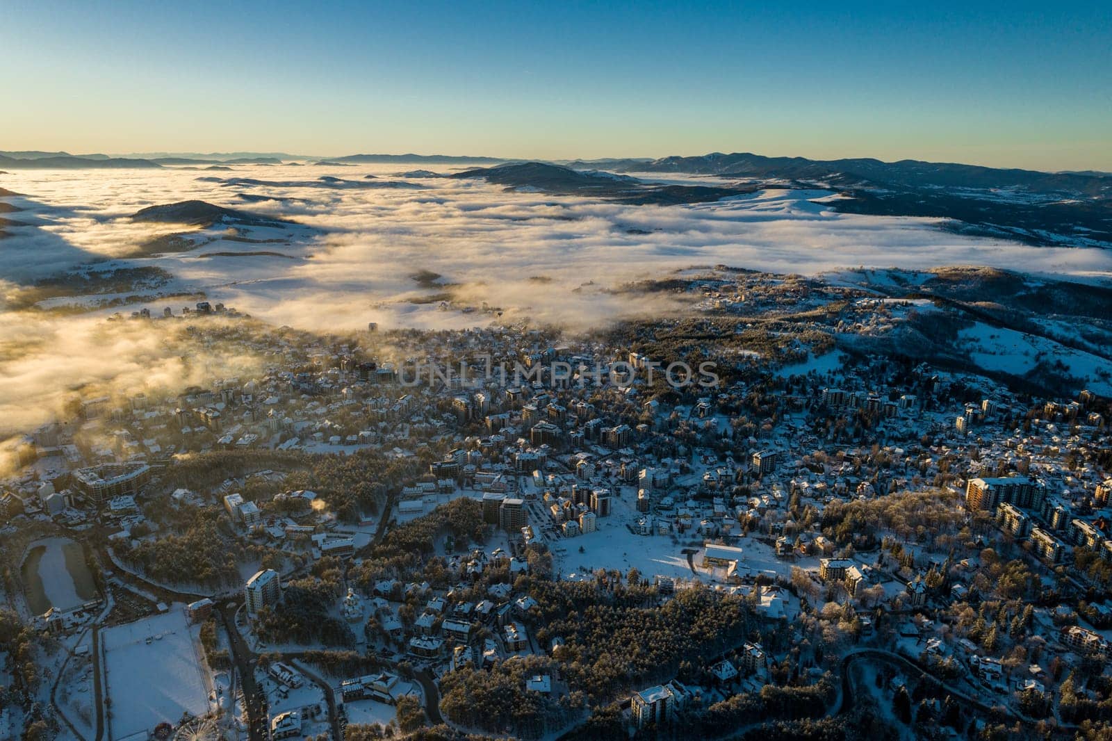 Panoramic aerial view of Zlatibor town and low cloud over Zlatibor Mountain at winter sunset, Cajetina, Serbia.