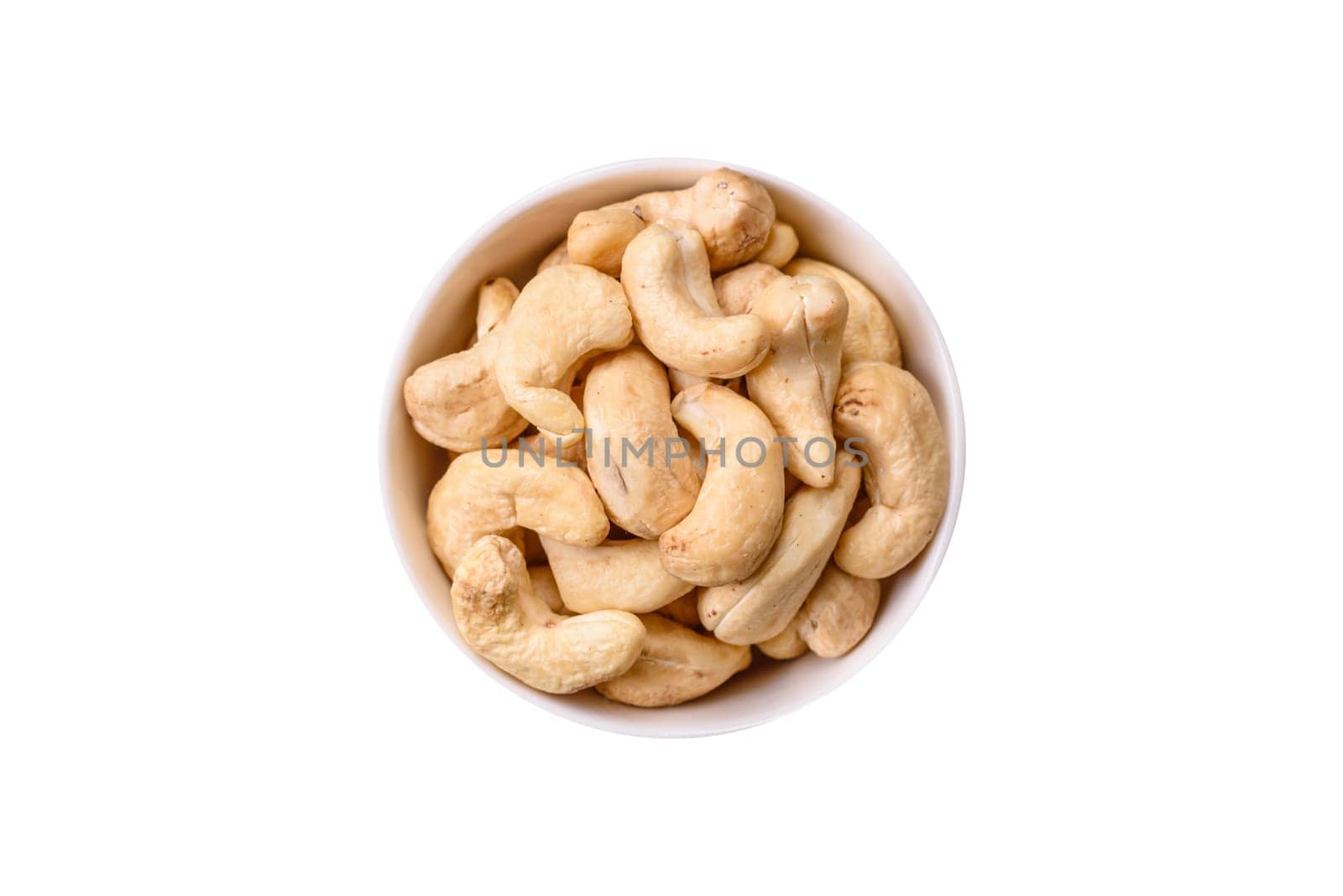 Delicious nutritious cashew nuts in ceramic bowl on dark concrete background