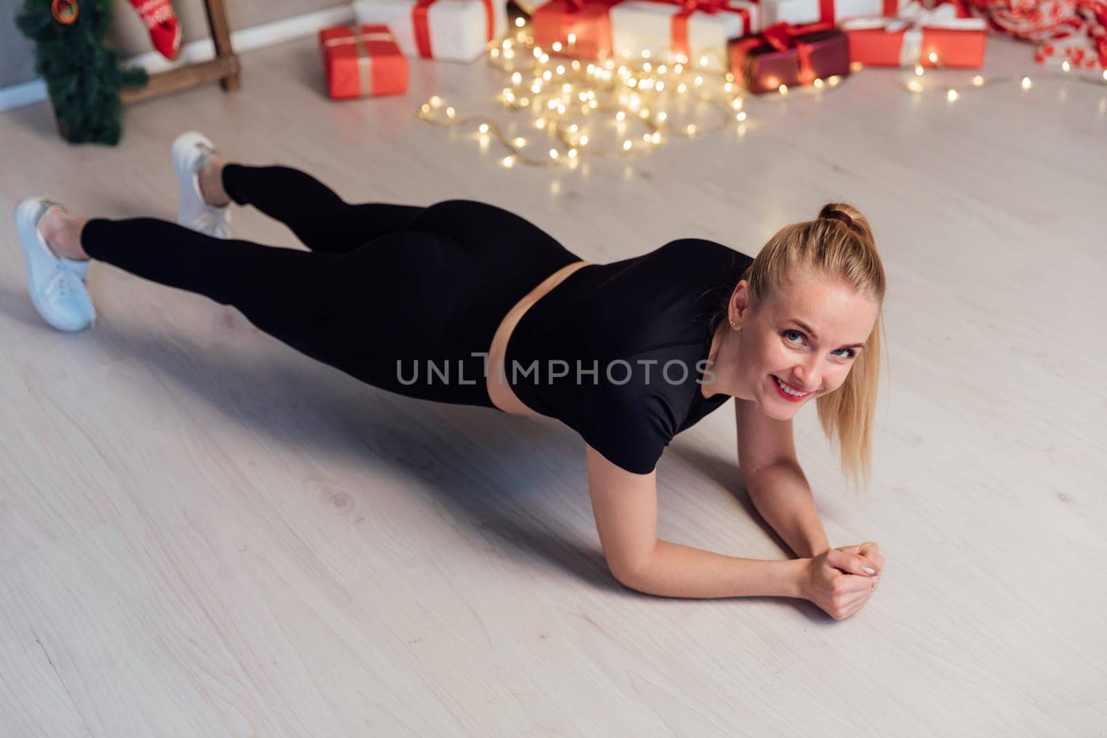 Athletic woman doing exercises in room with Christma